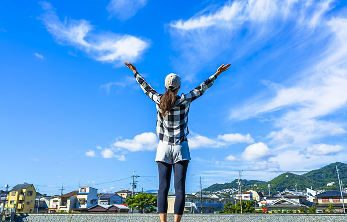 青空に手を広げる女性の写真